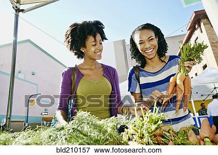 Stock Photo - Women shopping together at vegetable stand. Fotosearch