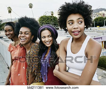 Stock Image - Women smiling on urban rooftop. Fotosearch