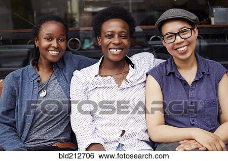 Stock Photograph - Women smiling outside coffee shop on city street. Fotosearch