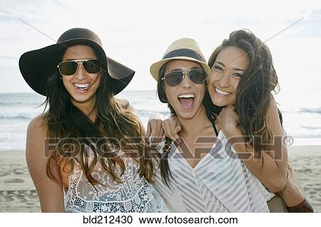 Stock Image - Women smiling together on beach. Fotosearch