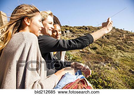 Women taking cell phone picture together on rural hillside View Large Photo Image Stock Photography - Women taking cell phone picture together on rural hillside. Fotosearch