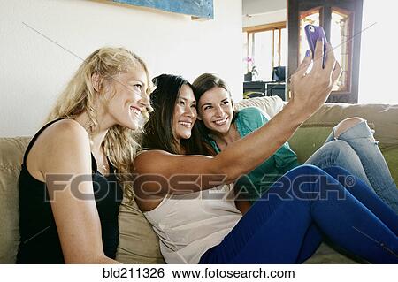 Women taking self-portraits together on sofa View Large Photo Image Stock Photograph - Women taking self-portraits together on sofa. Fotosearch