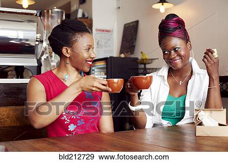 Stock Photo - Women toasting each other with coffee in cafe. Fotosearch