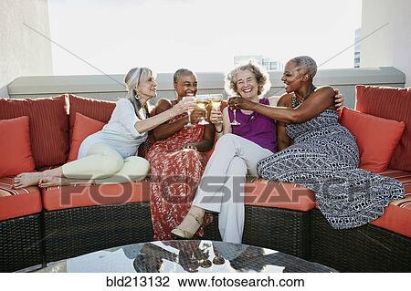 Stock Image - Women toasting each other with wine on urban rooftop. Fotosearch
