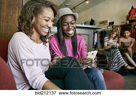 Women using cell phone in store View Large Photo Image Stock Photo - Women using cell phone in store. Fotosearch