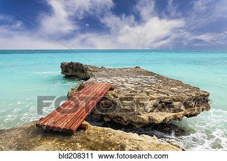 Stock Image - Wooden bridge across rocks on the coastline. Fotosearch