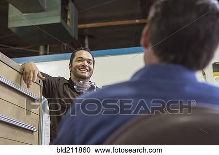 Stock Image - Worker and manager talking in warehouse. Fotosearch