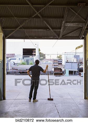 Worker holding broom in warehouse View Large Photo Image Stock Image - Worker holding broom in warehouse. Fotosearch