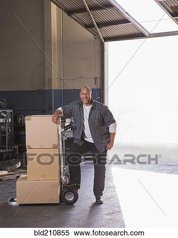 Worker with boxes on hand truck in warehouse View Large Photo Image Stock Photography - Worker with boxes on hand truck in warehouse. Fotosearch