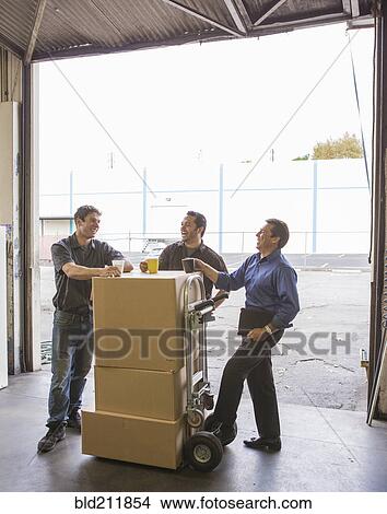 Picture - Workers enjoying coffee break at warehouse loading dock. Fotosearch