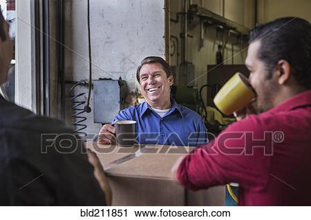 Stock Image - Workers enjoying coffee break in warehouse. Fotosearch