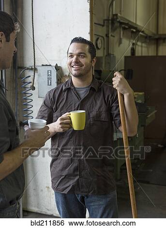 Stock Photograph - Workers having coffee together in warehouse. Fotosearch