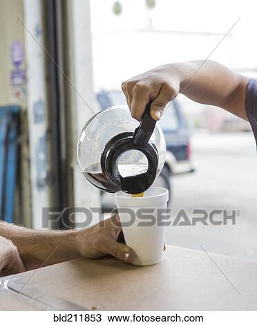 Workers pouring cup of coffee in warehouse View Large Photo Image Stock Image - Workers pouring cup of coffee in warehouse. Fotosearch