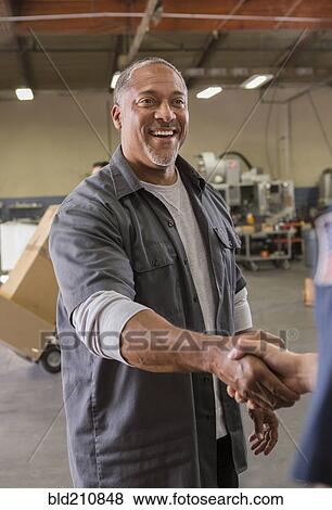 Workers shaking hands in warehouse View Large Photo Image Stock Photo - Workers shaking hands in warehouse. Fotosearch