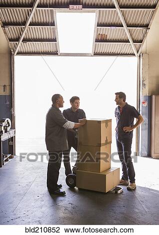 Stock Image - Workers talking in warehouse. Fotosearch