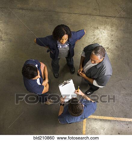 Stock Image - Workers talking in warehouse. Fotosearch