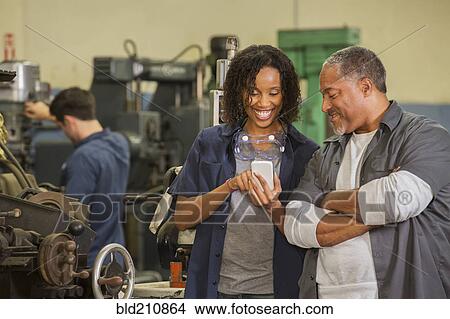 Picture - Workers using cell phone in warehouse. Fotosearch