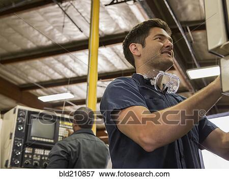 Stock Photo - Workers using machinery in warehouse. Fotosearch