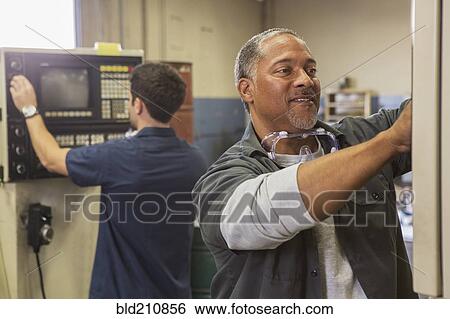 Stock Photograph - Workers using machinery in warehouse. Fotosearch