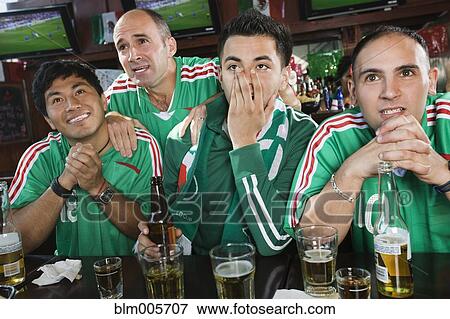 Stock Photo - Worried men watching television in sports bar. Fotosearch