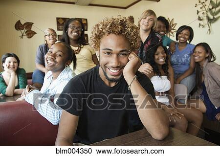 Stock Image - Young man in diner with group of young women in background. Fotosearch