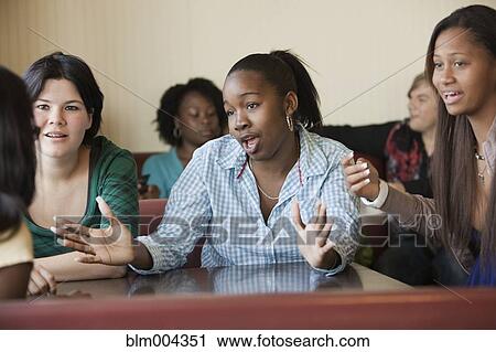 Stock Image - Young women talking in diner. Fotosearch