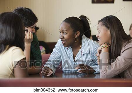 Stock Image - Young women talking in diner. Fotosearch