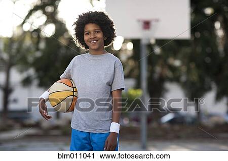 Stock Image - African American boy holding basketball. Fotosearch
