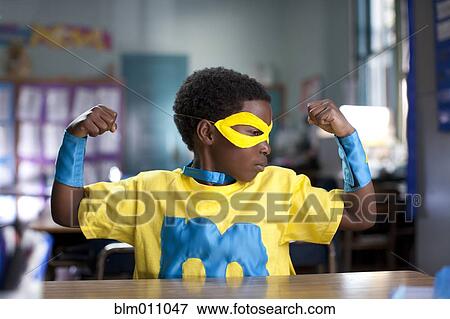 Stock Photo - African American boy wearing superhero costume in classroom. Fotosearch