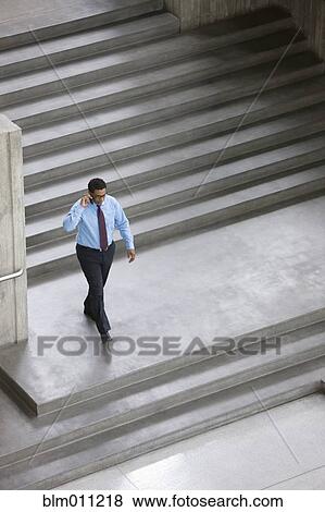 Stock Photo - African American businessman using cell phone outdoors. Fotosearch