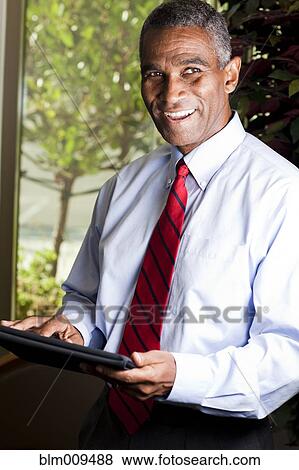 Stock Photo - African American businessman using electronic tablet. Fotosearch