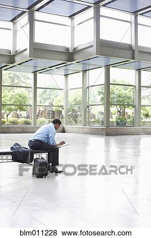 Stock Photo - African American businessman using digital tablet in lobby. Fotosearch