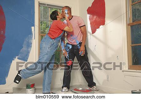 Stock Photo - African American couple painting wall and kissing. Fotosearch