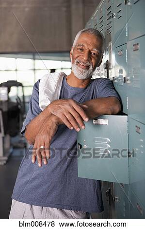 Stock Photo - African American leaning on lockers in health club. Fotosearch