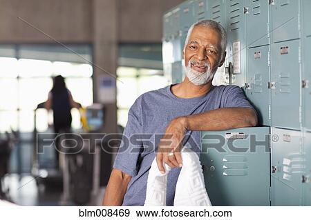 Stock Photo - African American man leaning on lockers in health club. Fotosearch