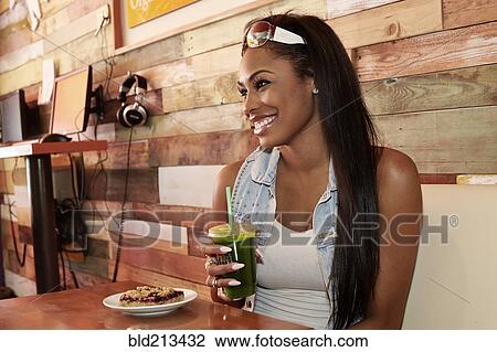 Stock Image - African American woman having juice in cafe. Fotosearch