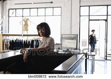Stock Image - African American woman working in clothing store. Fotosearch