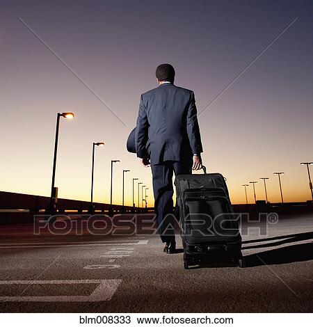 African businessman pulling luggage in parking lot View Large Photo Image Stock Image - African businessman pulling luggage in parking lot. Fotosearch