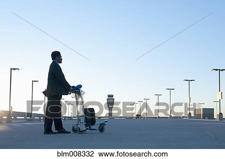 African businessman pushing luggage cart in airport parking lot View Large Photo Image Stock Image - African businessman pushing luggage cart in airport parking lot. Fotosearch
