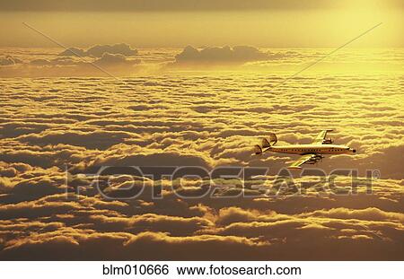 Airplane flying over clouds at sunset View Large Photo Image Stock Photograph - Airplane flying over clouds at sunset. Fotosearch