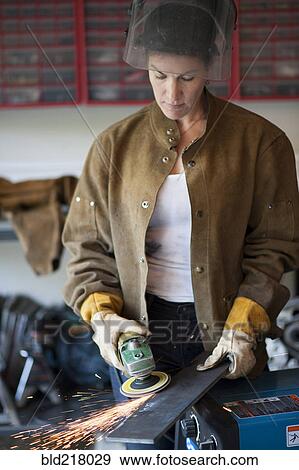 Stock Photo - Artisan grinding metal in garage workshop. Fotosearch