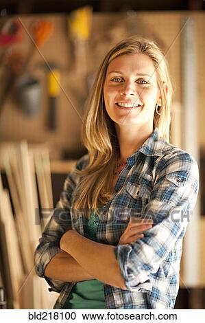 Stock Image - Artisan smiling in garage workshop. Fotosearch
