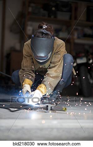 Stock Image - Artisan welding metal in workshop. Fotosearch