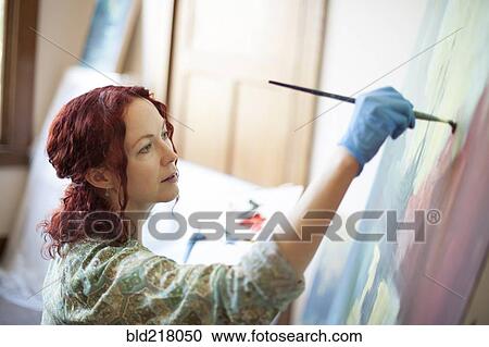 Stock Image - Artist painting on canvas in studio. Fotosearch
