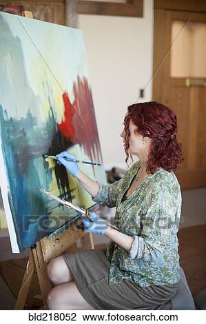 Stock Image - Artist painting on canvas in studio. Fotosearch