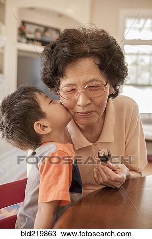 Asian boy kissing grandmother at table View Large Photo Image Stock Image - Asian boy kissing grandmother at table. Fotosearch
