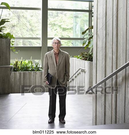 Stock Photography - Asian businessman standing in lobby. Fotosearch