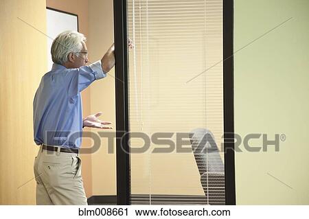Stock Image - Asian businessman standing in office doorway talking. Fotosearch
