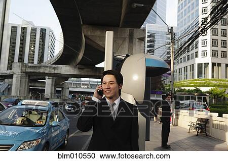 Asian businessman talking on cell phone outdoors View Large Photo Image Stock Image - Asian businessman talking on cell phone outdoors. Fotosearch