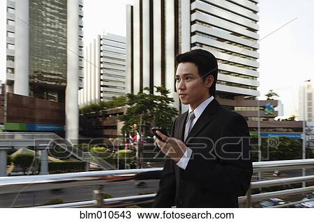Asian businessman text messaging on cell phone outdoors View Large Photo Image Stock Image - Asian businessman text messaging on cell phone outdoors. Fotosearch